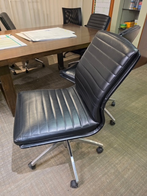 Black vinyl desk chair on chrome caster base, side view